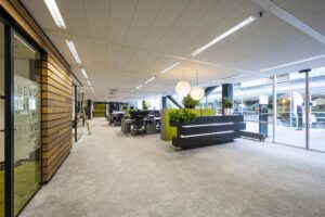 Modern open-plan office interior at Jacob Bontiusplaats with workstations, green accents, and a sleek reception area.